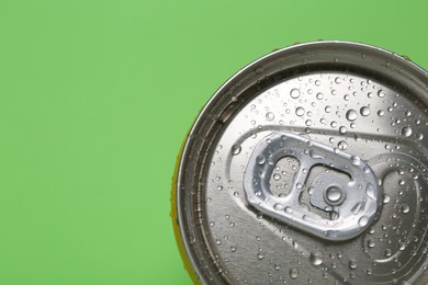 Photo of Energy drink in wet can on green background, top view. Space for text
