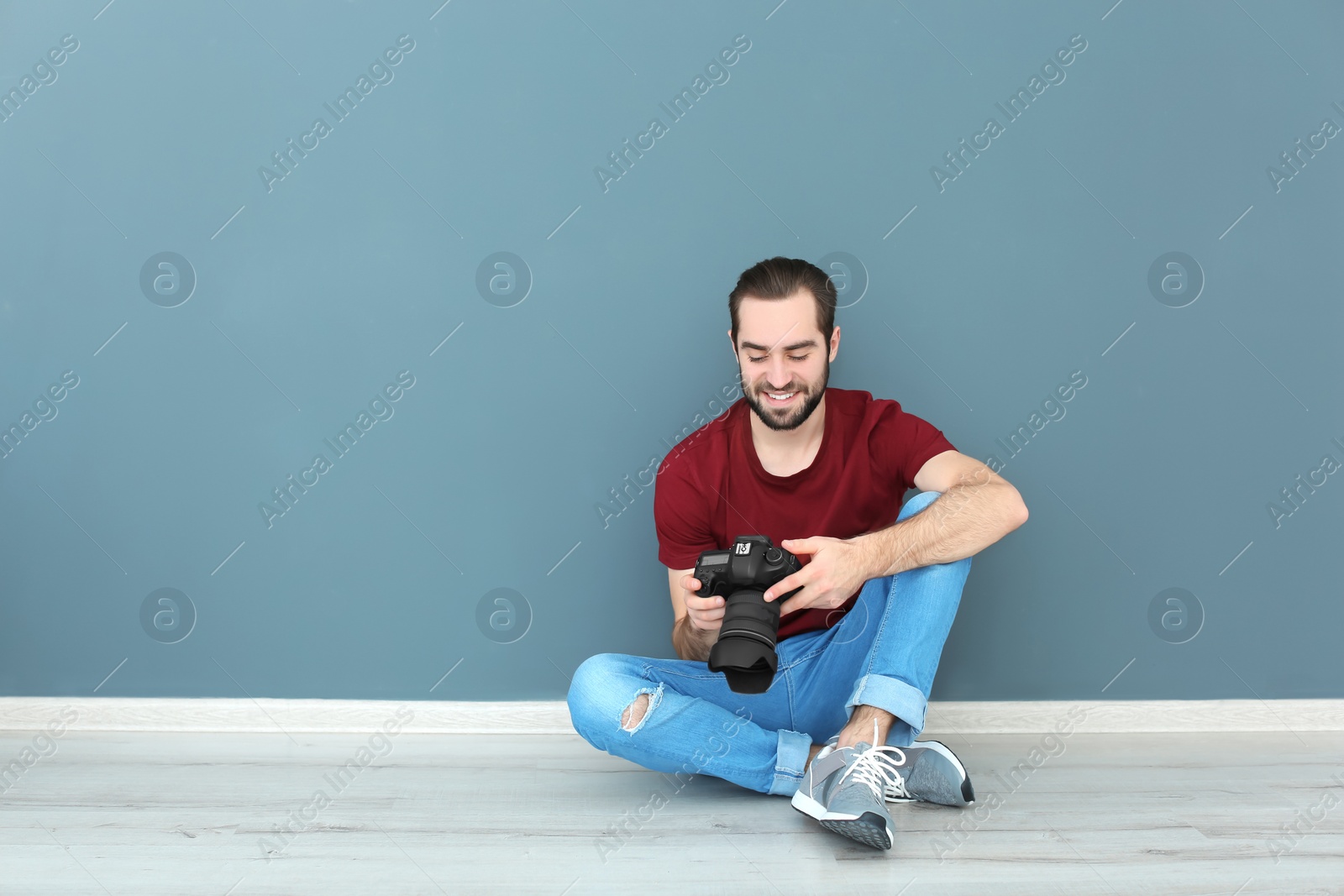 Photo of Young photographer with professional camera near color wall