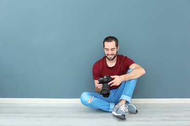 Young photographer with professional camera near color wall