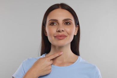 Photo of Endocrine system. Young woman doing thyroid self examination on light grey background