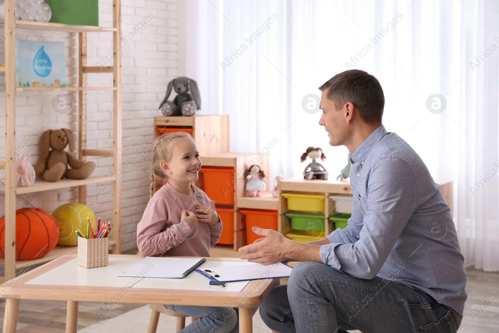 Photo of Child psychotherapist working with little girl in office