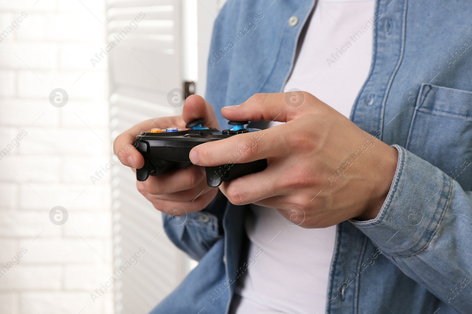 Photo of Man using wireless game controller indoors, closeup