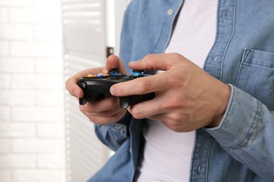 Photo of Man using wireless game controller indoors, closeup