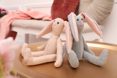 Photo of Cute toy rabbits on golden stand in room
