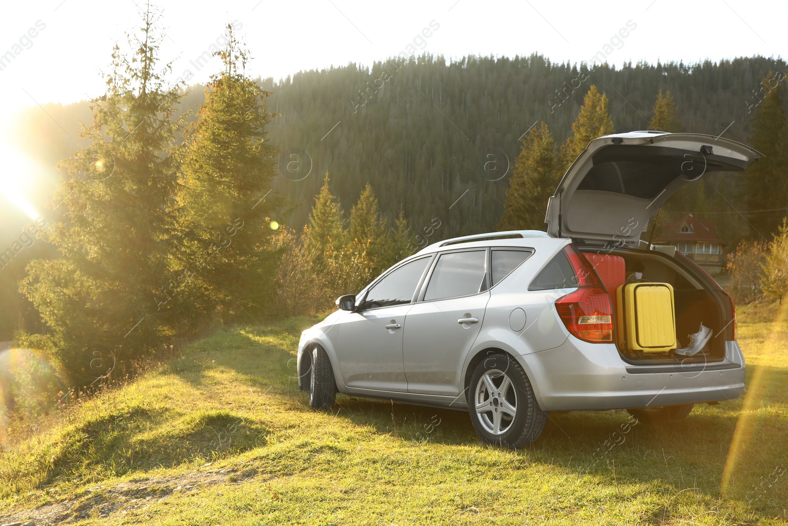 Photo of Gray modern car with suitcases in mountains on sunny day