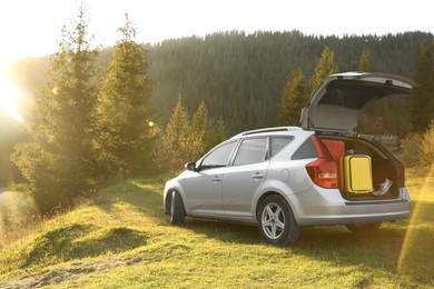 Gray modern car with suitcases in mountains on sunny day