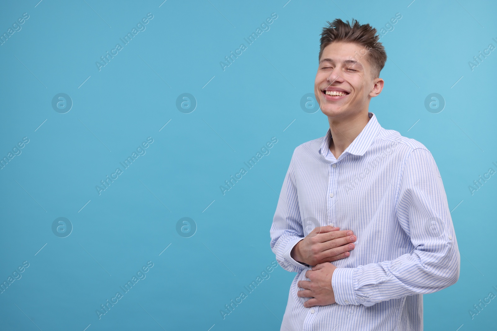 Photo of Young man laughing on light blue background. Space for text