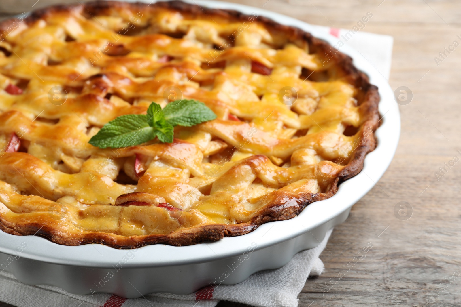 Photo of Traditional apple pie with mint on wooden table, closeup