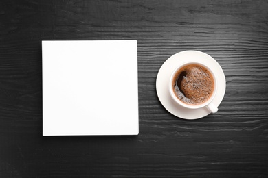 Blank paper sheets for brochure and cup of coffee on black wooden background, flat lay. Mock up