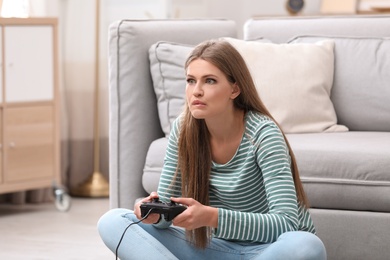 Emotional young woman playing video games at home