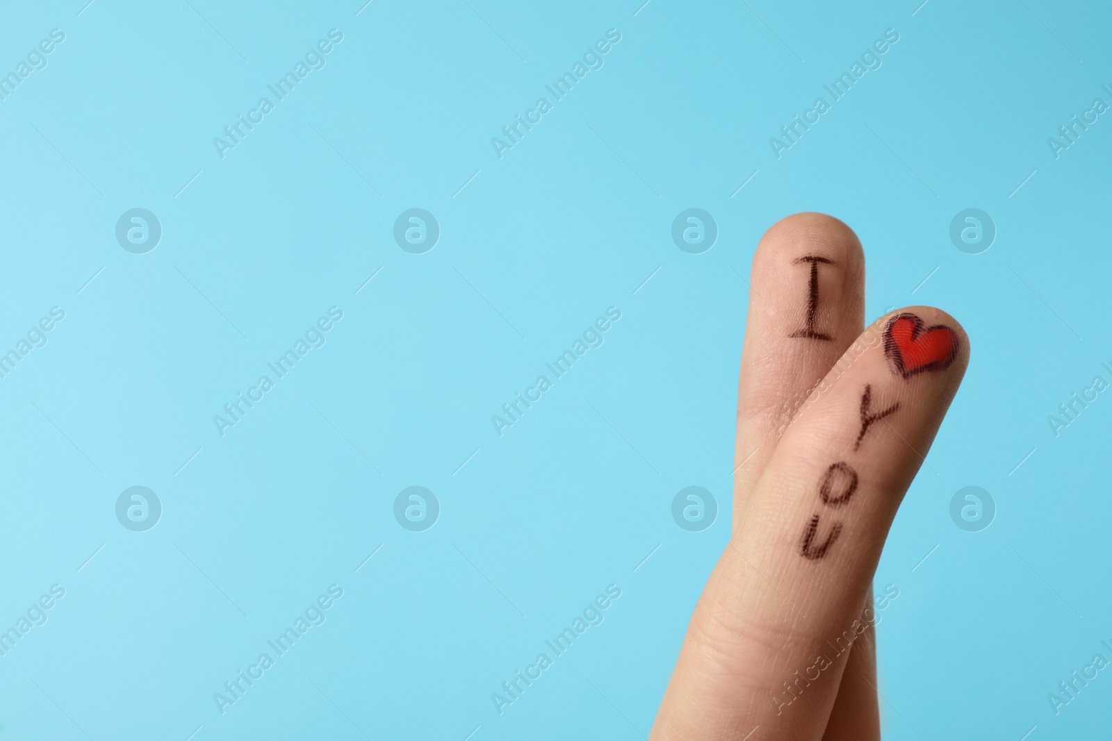 Photo of Fingers with phrase I Love You on light blue background