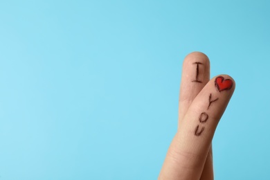 Photo of Fingers with phrase I Love You on light blue background