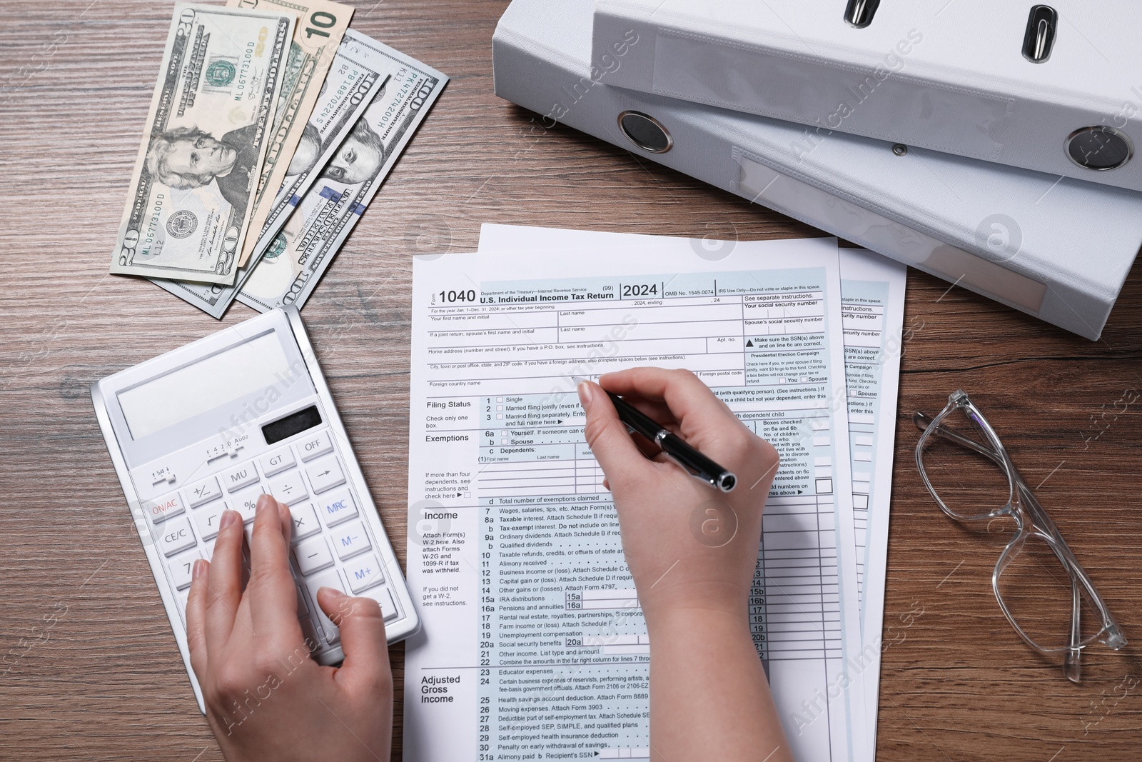 Photo of Payroll. Woman using calculator while working with tax return forms at wooden table, top view