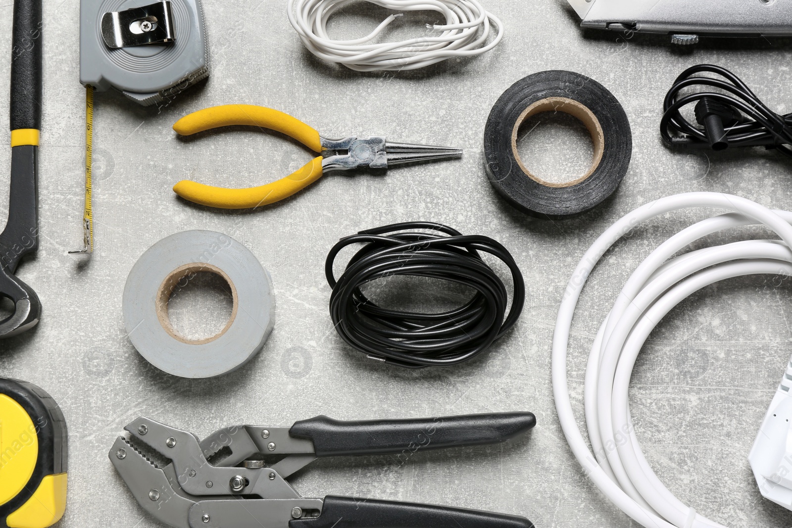 Photo of New wires and electrician's tools on grey table, flat lay