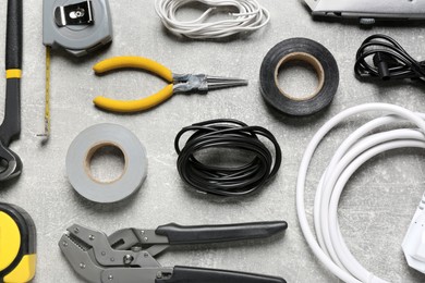 New wires and electrician's tools on grey table, flat lay