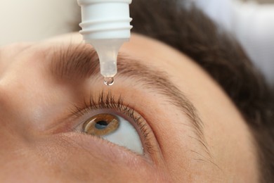 Photo of Closeup view of man using eye drops