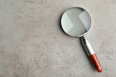 Top view of magnifier glass on light grey stone background, space for text. Find keywords concept