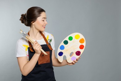 Photo of Woman with painting tools on grey background, space for text. Young artist