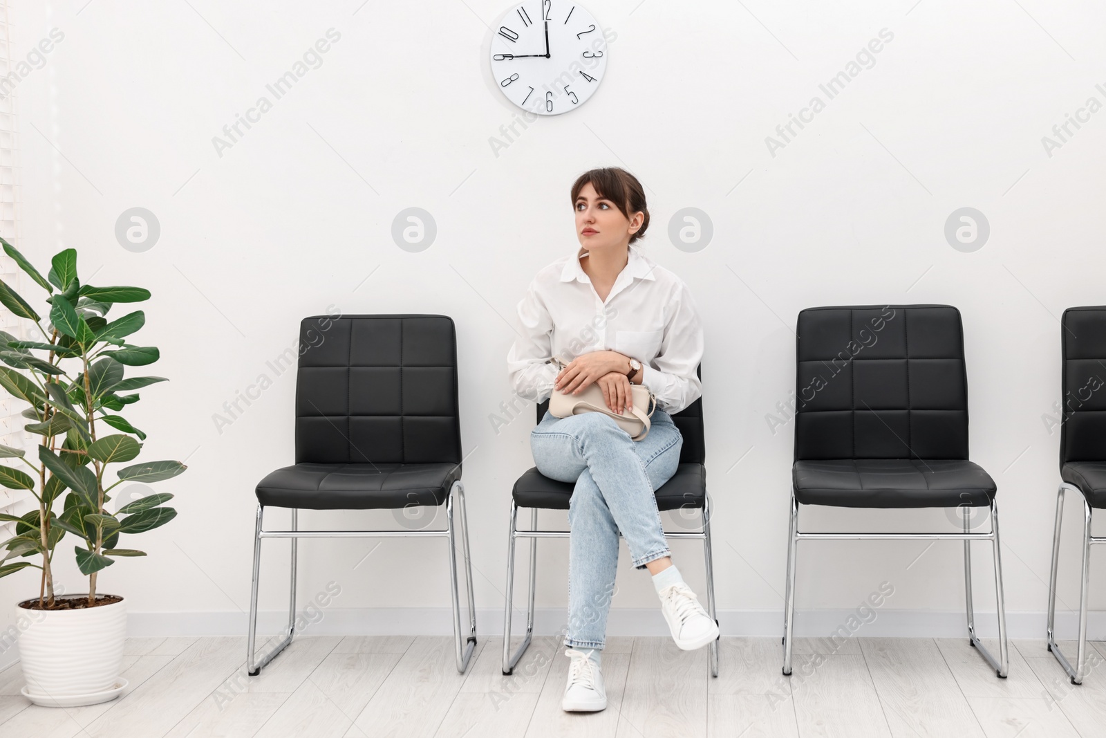 Photo of Woman sitting on chair and waiting for appointment indoors