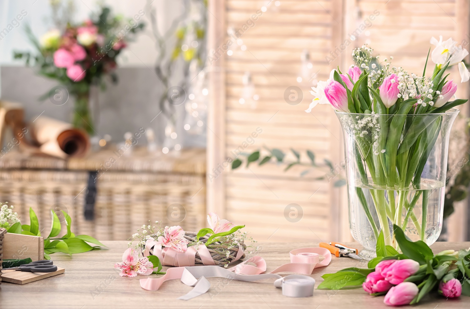 Photo of Decorator's workplace with beautiful flowers and unfinished wreath on table