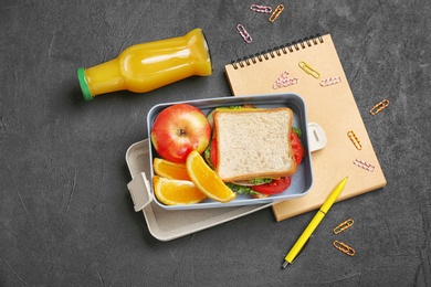 Photo of Flat lay composition with lunch box, appetizing food and stationery on dark background