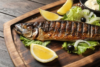 Photo of Wooden board with delicious grilled fish, closeup