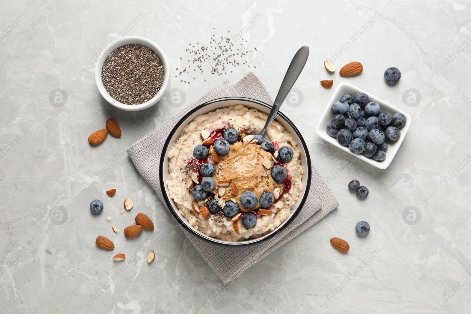 Photo of Tasty oatmeal porridge with toppings served on light grey table, flat lay