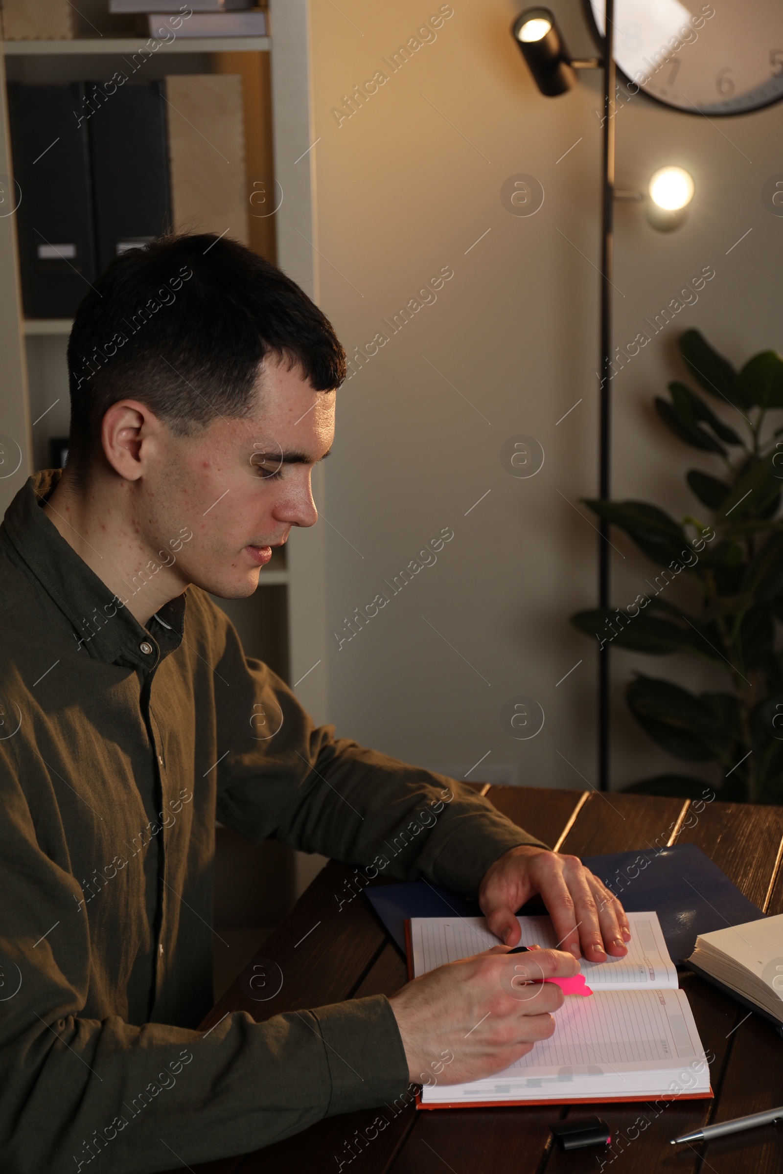 Photo of Man taking notes at wooden table in office
