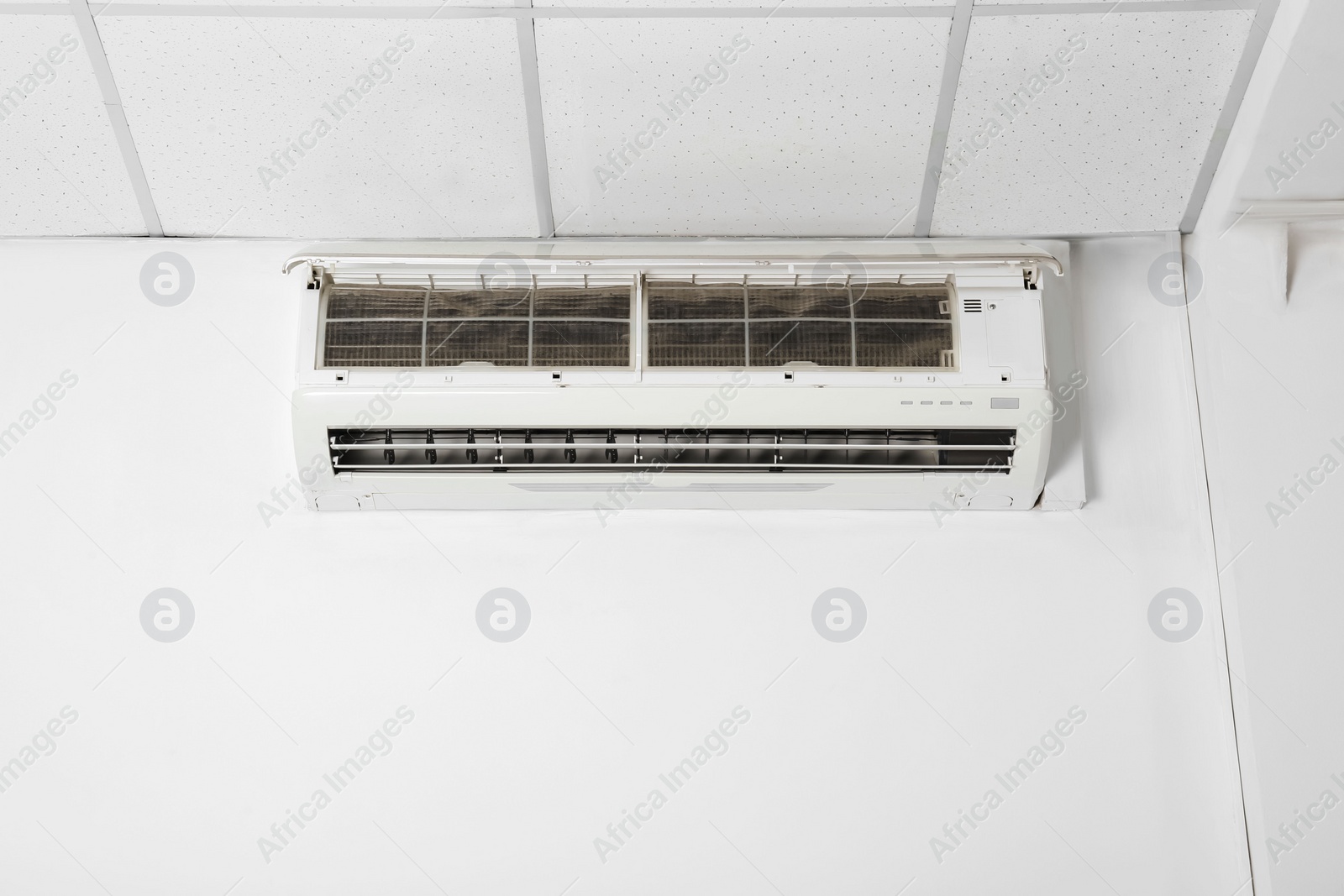 Photo of Modern air conditioner on white wall indoors. Space for text