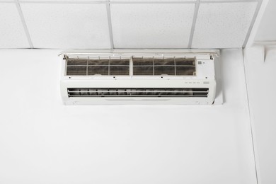 Modern air conditioner on white wall indoors. Space for text