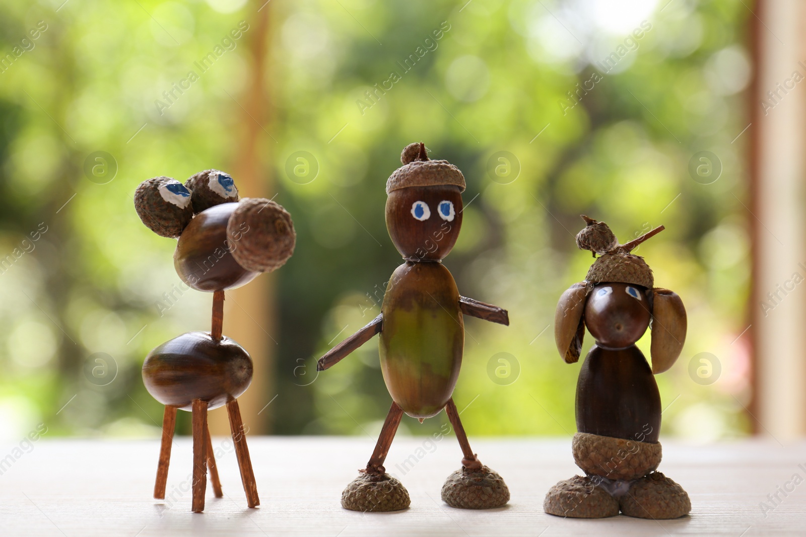 Photo of Cute figures made of acorns on white wooden table