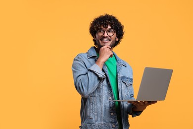 Smiling man with laptop on yellow background, space for text