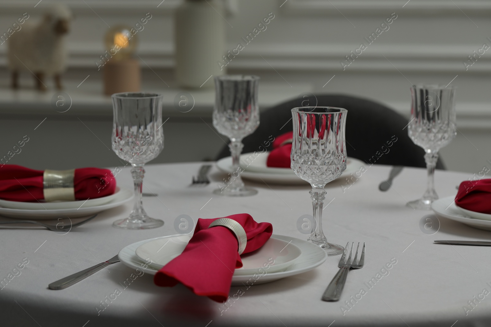 Photo of Color accent table setting. Glasses, plates, cutlery and pink napkins on table indoors