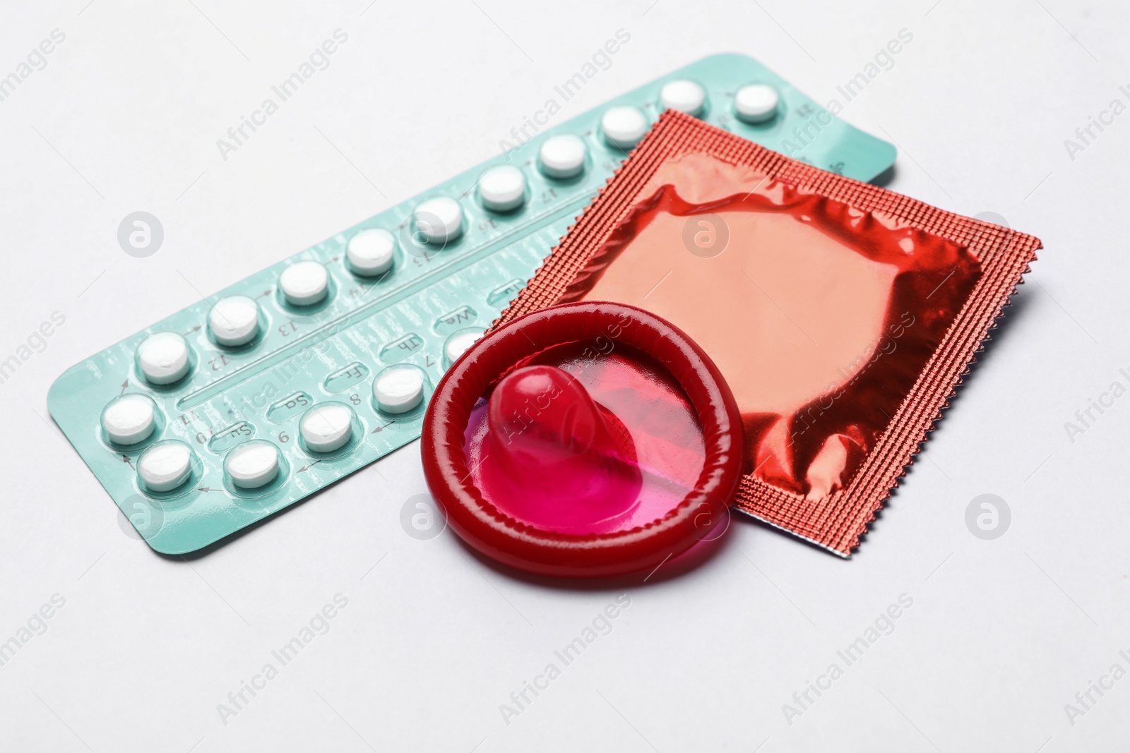 Photo of Condoms and birth control pills on white background. Safe sex concept