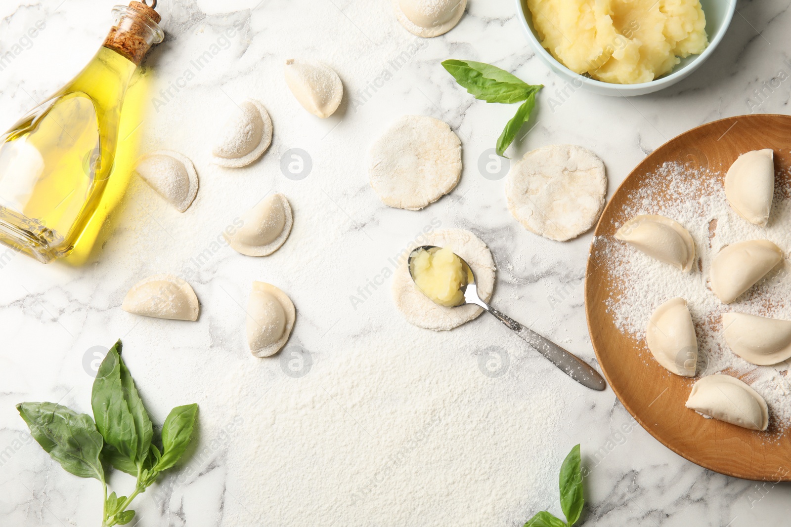 Photo of Flat lay composition with raw dumplings, oil and mashed potatoes on marble background. Process of cooking