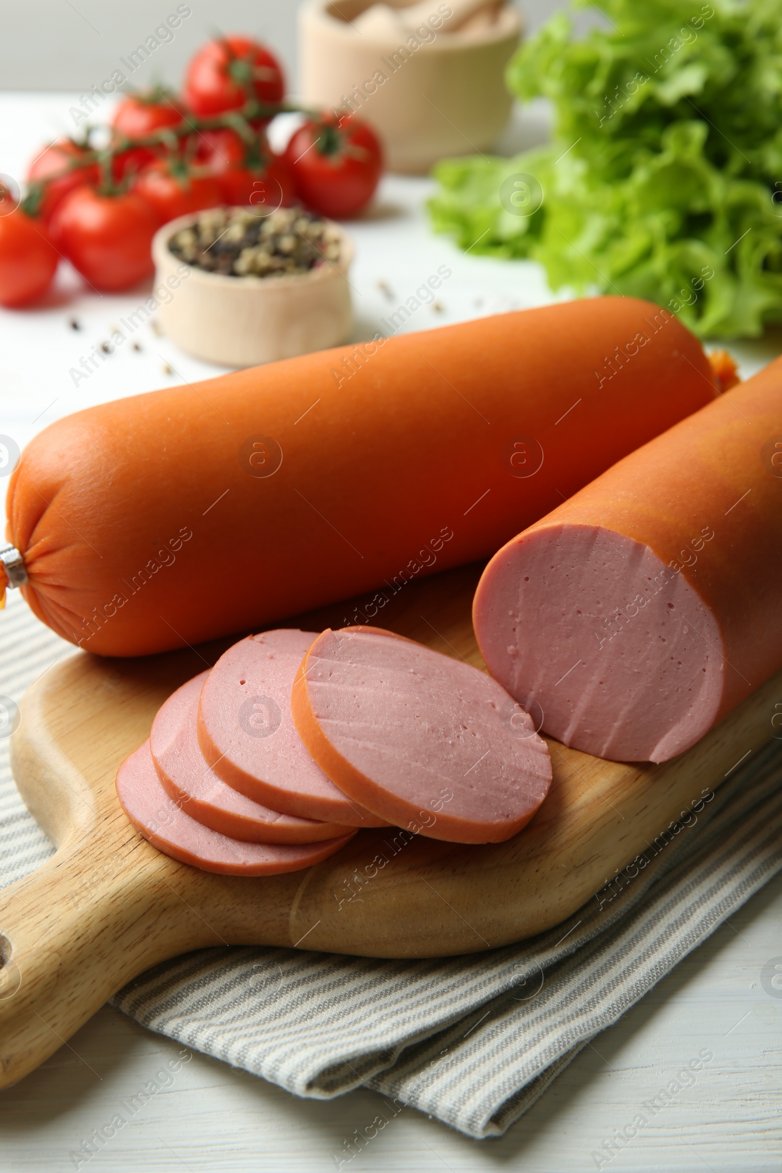 Photo of Board with tasty boiled sausages on white wooden table