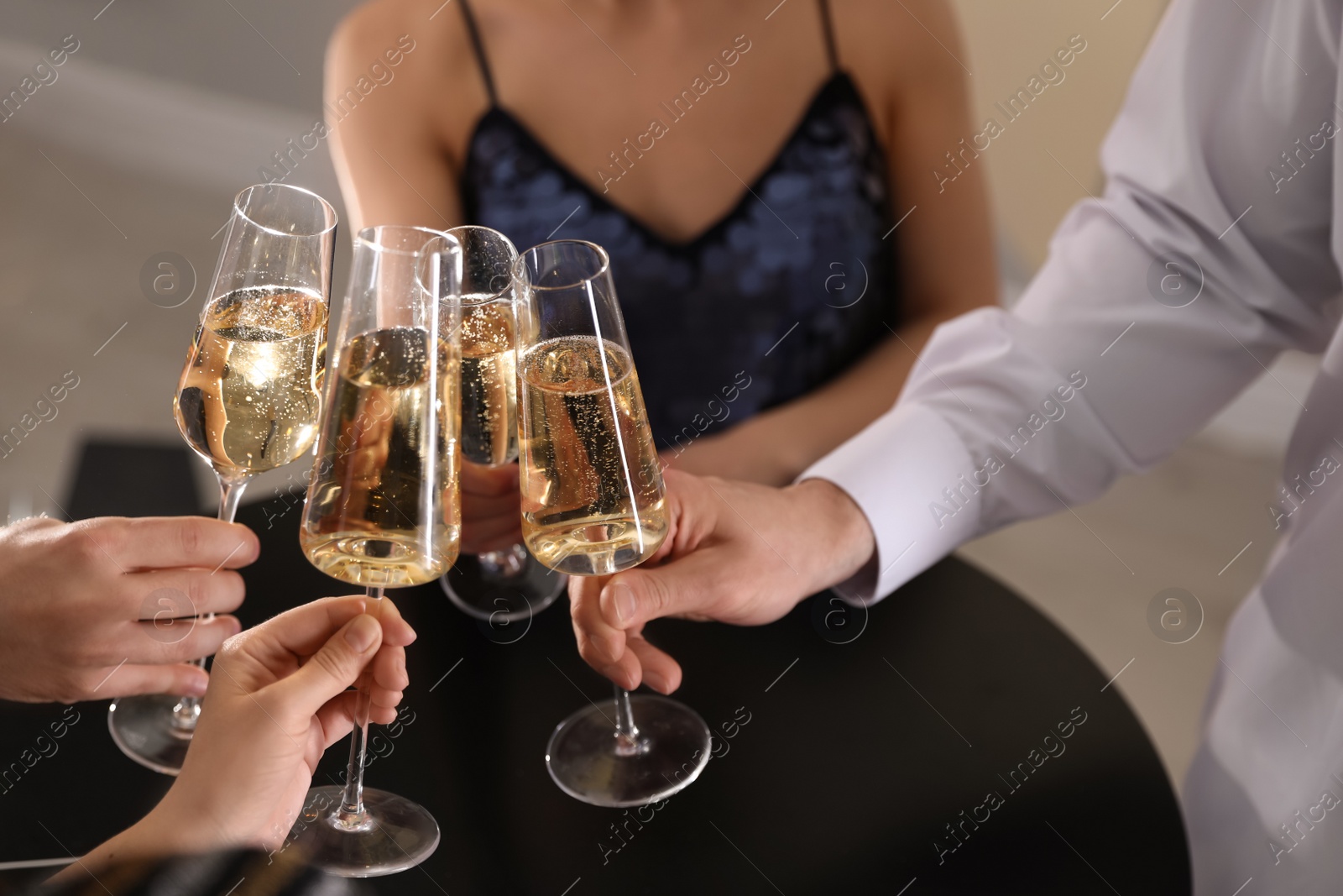 Photo of Friends clinking glasses of champagne in restaurant, closeup