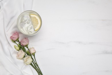 Refreshing drink, flowers and delicate fabric on white marble table, flat lay. Space for text