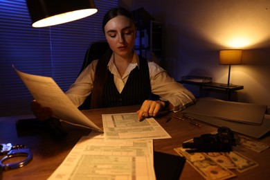 Professional detective working with documents in office at night