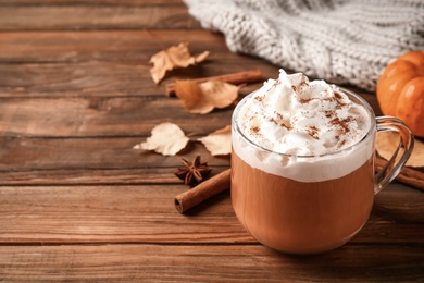 Photo of Delicious pumpkin latte on wooden table, closeup. Space for text