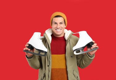 Emotional man with ice skates on red background