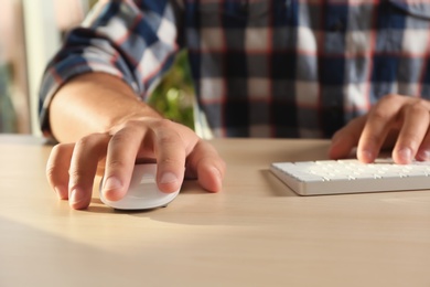 Photo of Man using computer mouse and keyboard at table, closeup