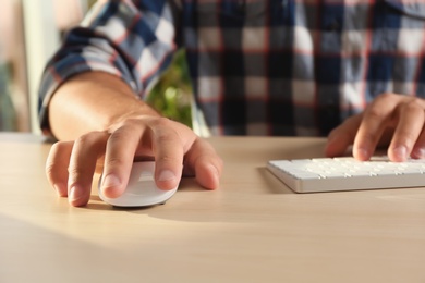 Man using computer mouse and keyboard at table, closeup