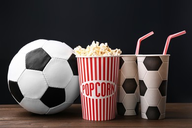 Photo of Football ball with popcorn and cups on wooden table