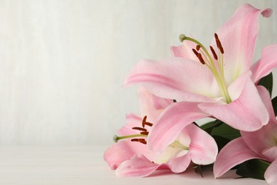 Beautiful pink lily flowers on white table, closeup. Space for text