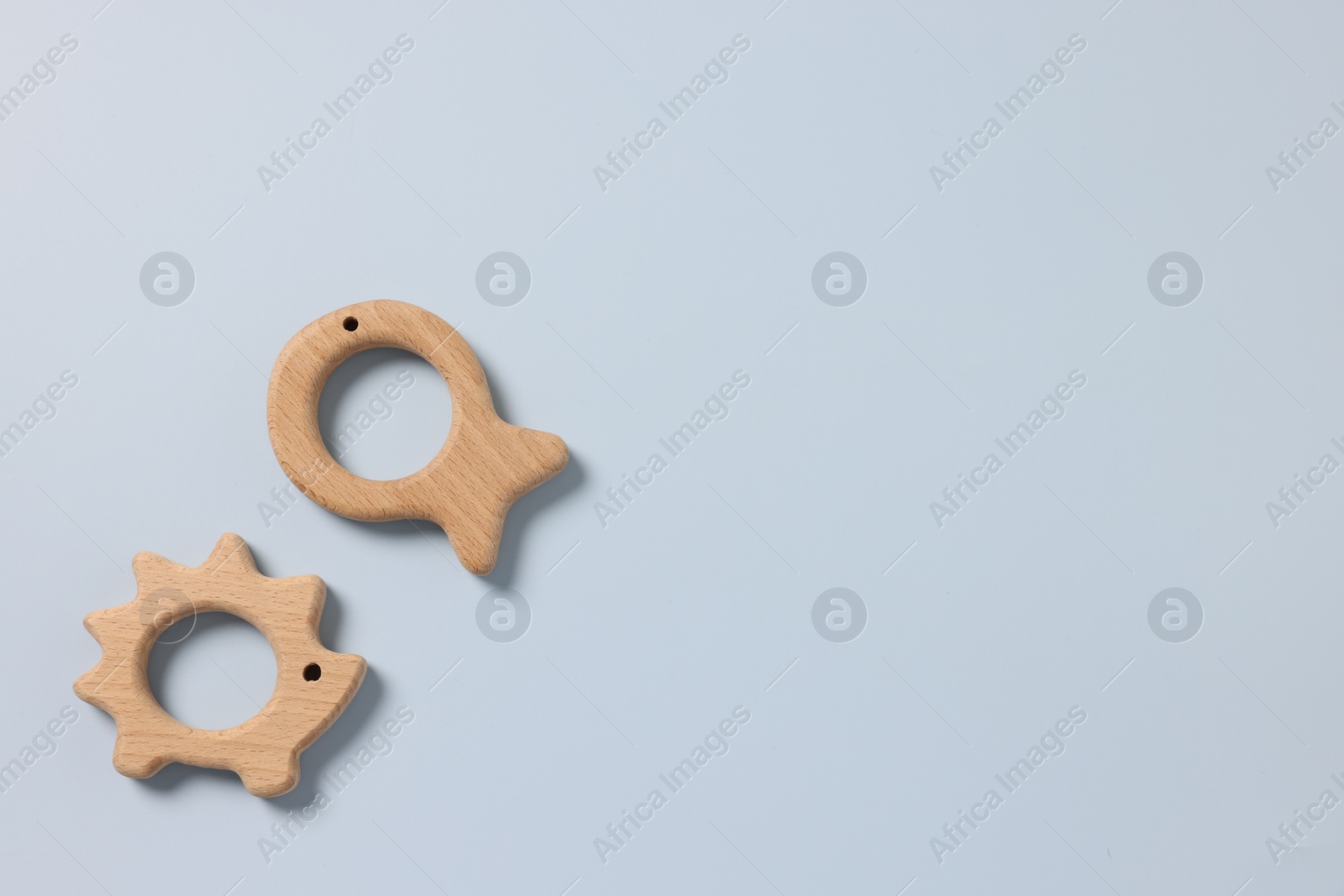 Photo of Baby accessories. Wooden teethers on light blue background, top view