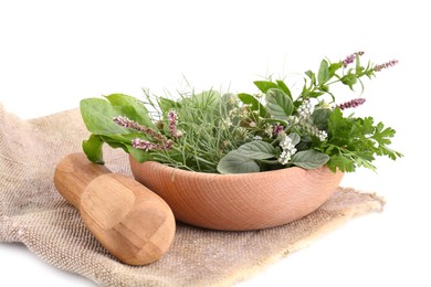 Photo of Wooden mortar, pestle and different herbs on cloth against white background