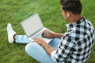 Photo of Portrait of young man with laptop outdoors. Space for design