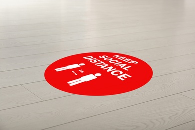 Image of Sign KEEP SOCIAL DISTANCE on floor indoors. Coronavirus pandemic