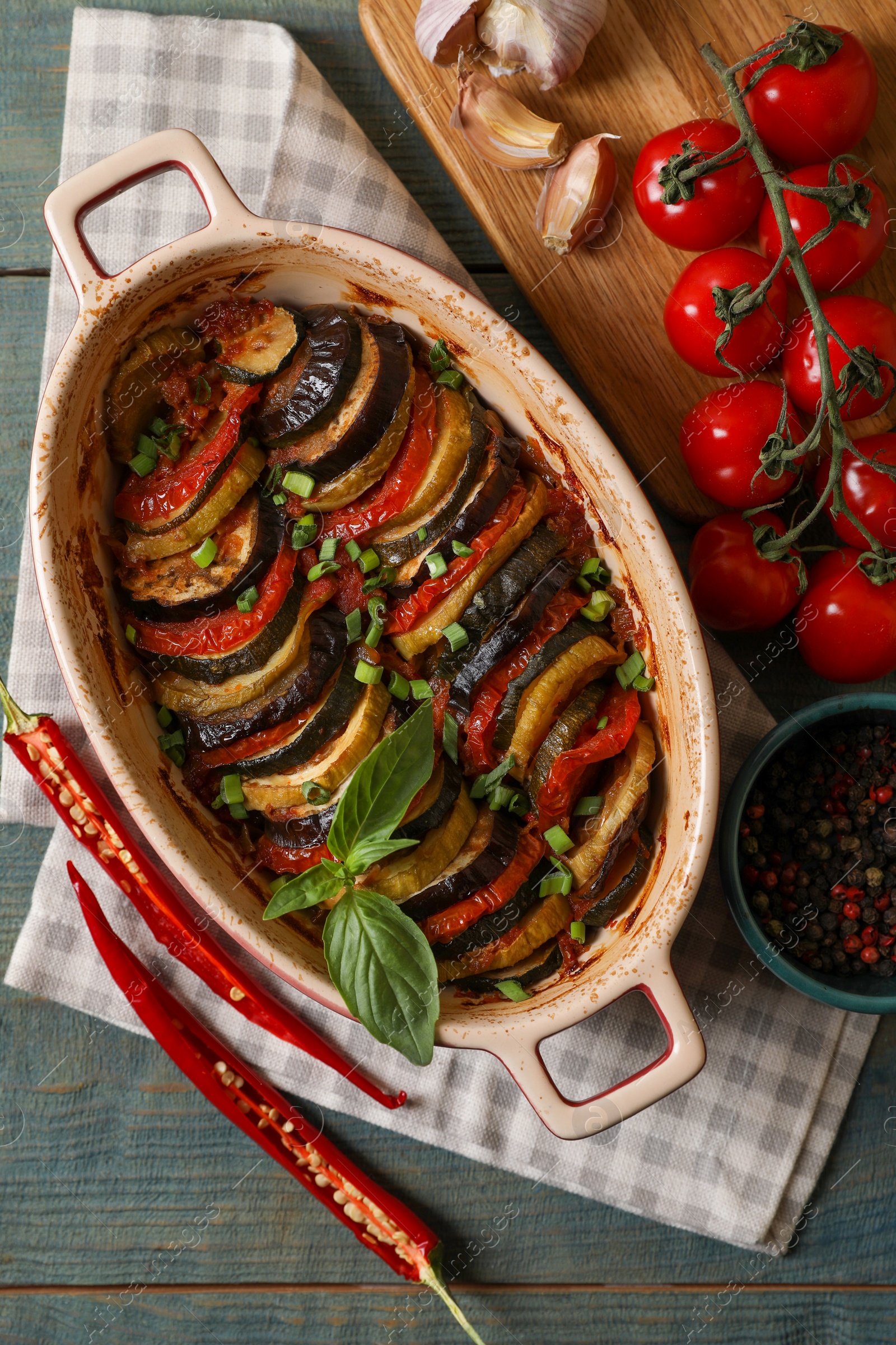 Photo of Delicious ratatouille and ingredients on wooden table, flat lay